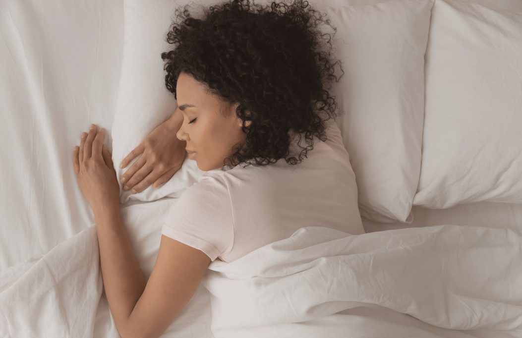 Woman curly hair asleep in white bed
