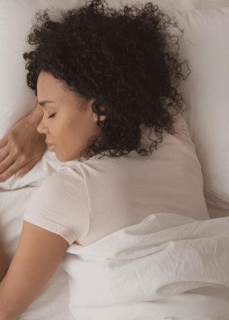 Woman curly hair asleep in white bed